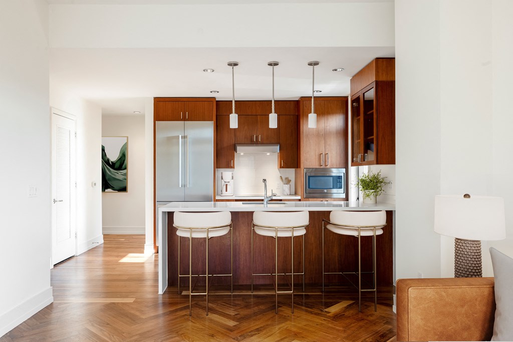 a kitchen with wooden cabinets and a bar with white stools