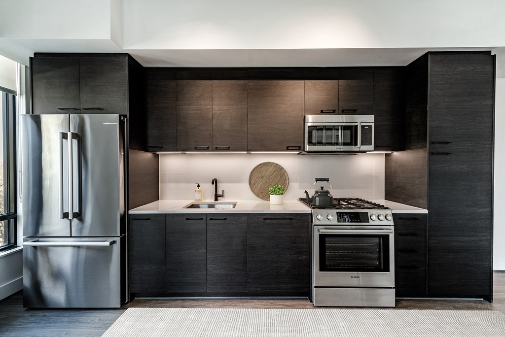 a kitchen with black cabinets and stainless steel appliances