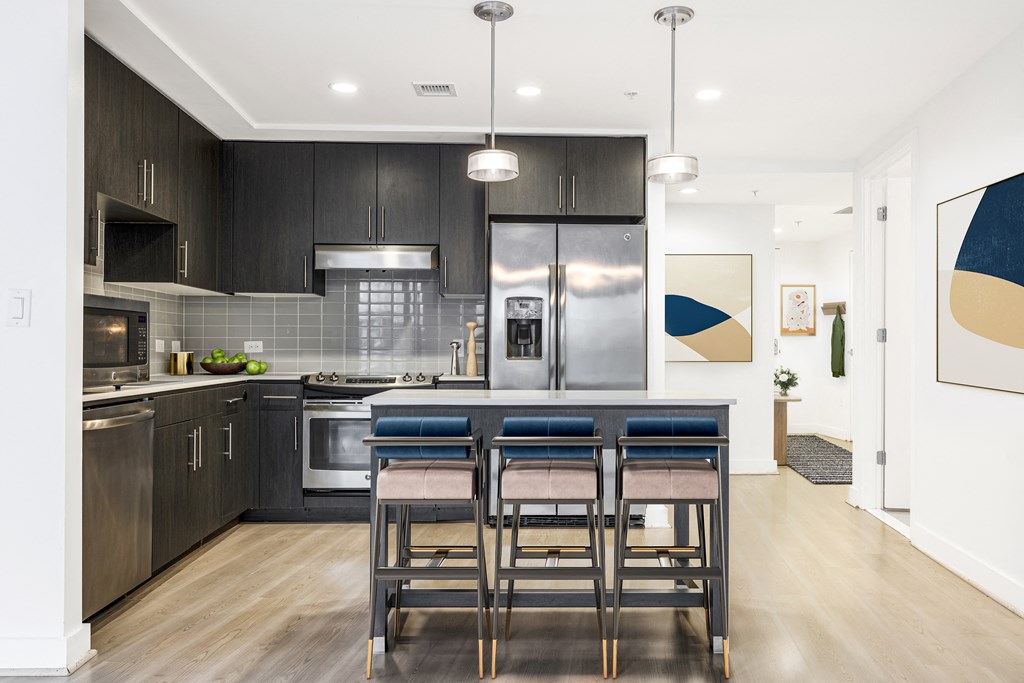 a kitchen with dark cabinets and a large island with a breakfast bar