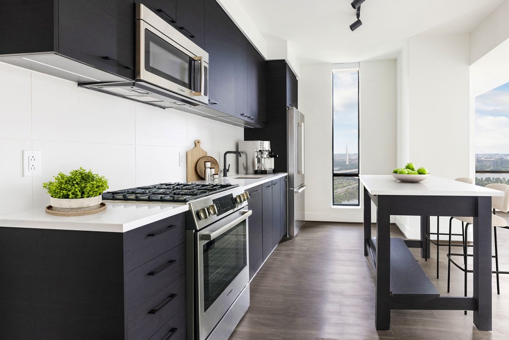 a kitchen with black cabinets and a white counter top and a stove and microwave