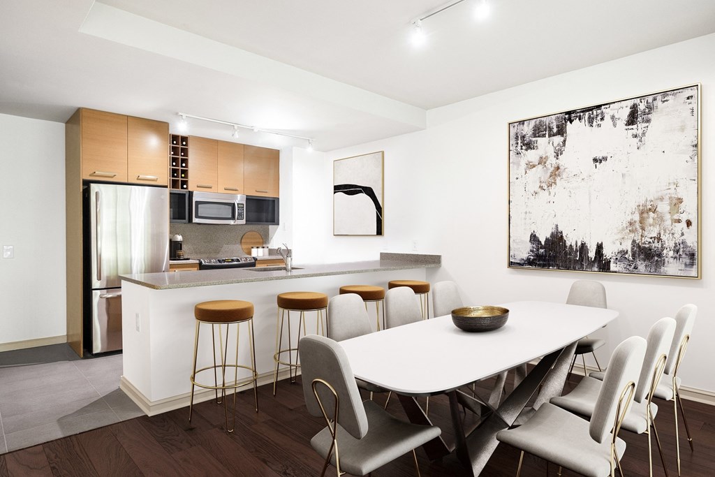 a dining area with a white table and chairs and a kitchen in the background