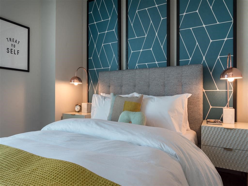 a bedroom with a bed and a blue wall with geometric patterns