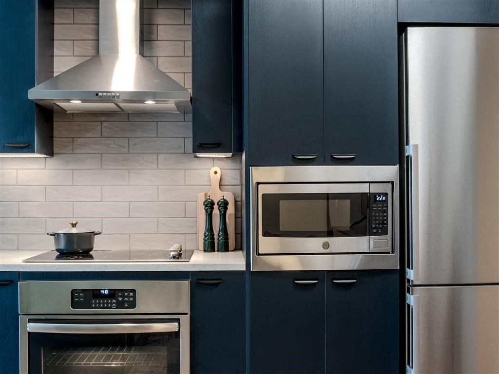a kitchen with blue cabinets and a stainless steel microwave