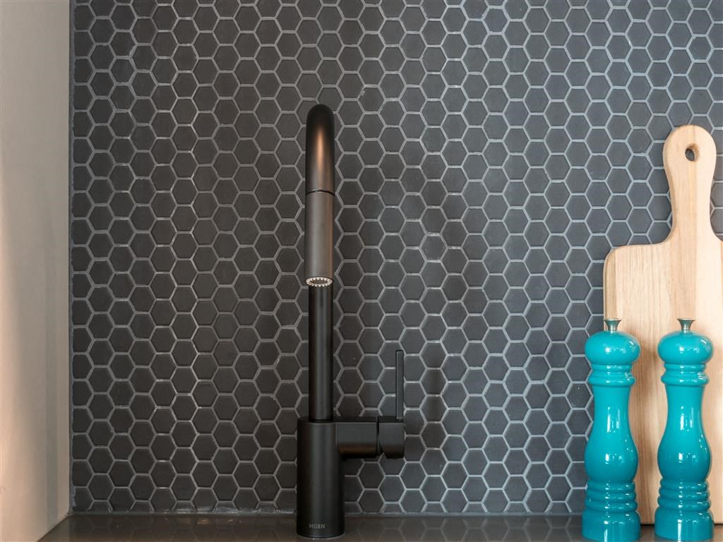 a black faucet in a kitchen with blue vases