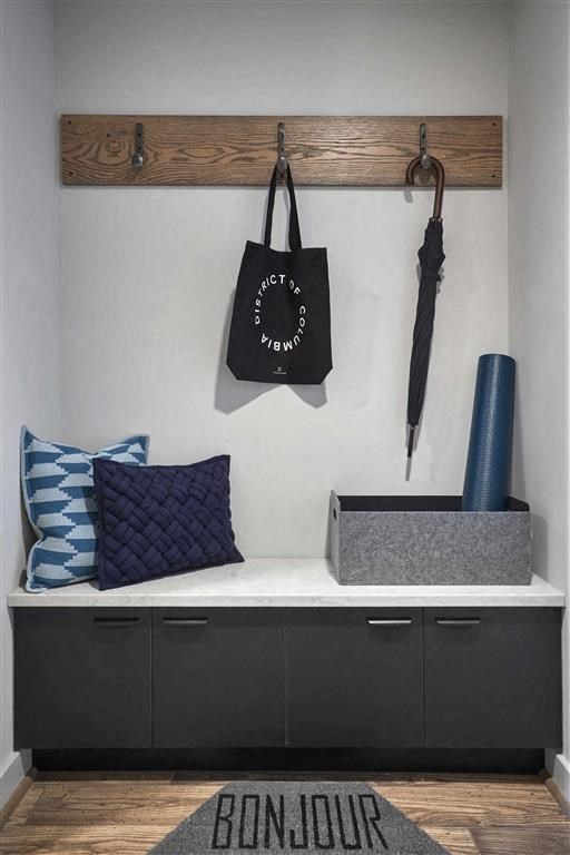 a room with a bench with pillows and bags on the wall