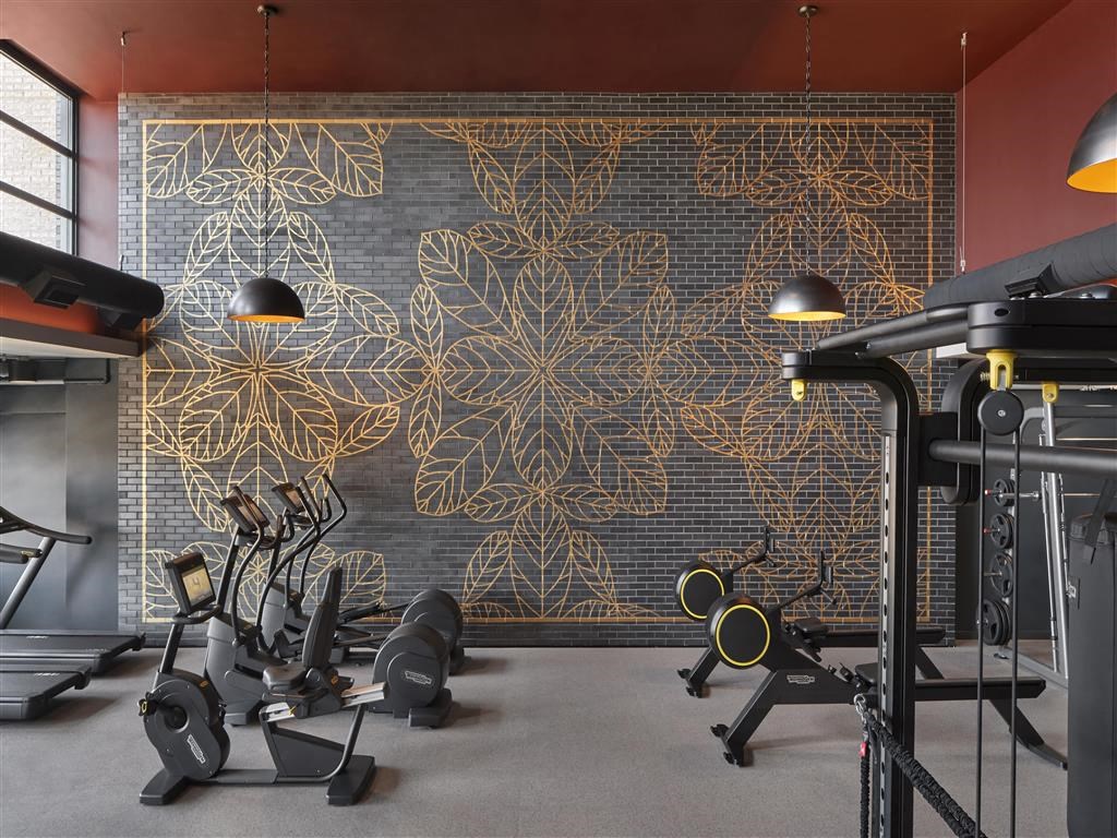 a gym with exercise machines in front of a wall with a gold leaf mural