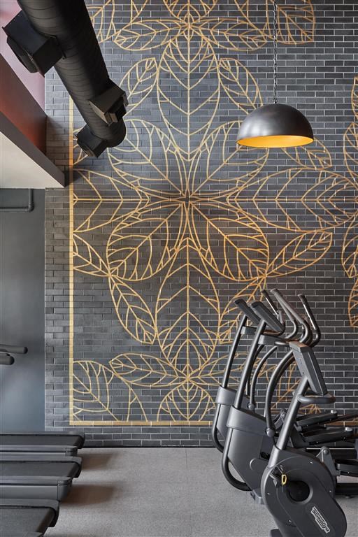 a gym with exercise machines and a mural on the wall