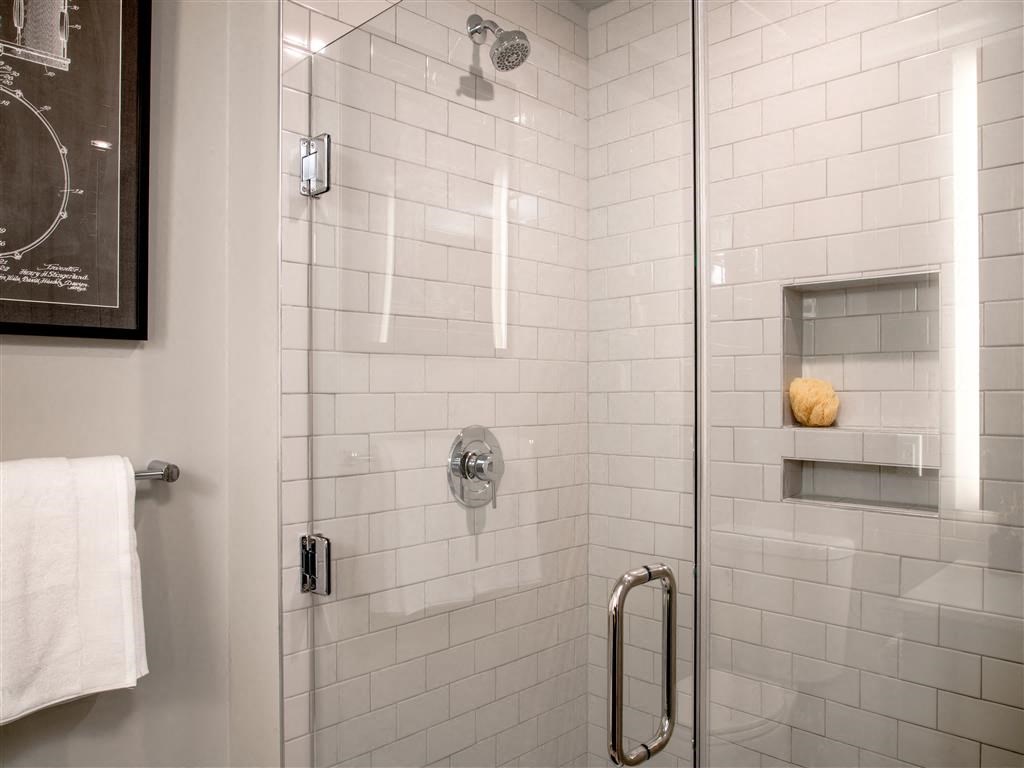 a white tiled shower in a bathroom with a glass door