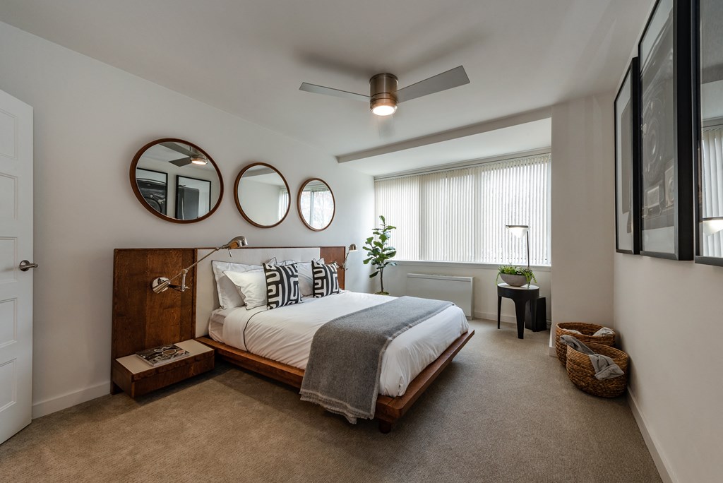 a bedroom with a bed and two mirrors on the wall