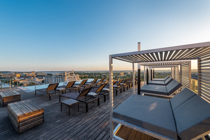 a rooftop deck with tables and chairs and a view of the city