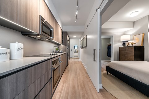 a bedroom with a bed and a kitchen with wooden cabinets