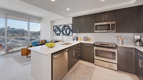 A modern kitchen with dark brown cabinets and stainless steel appliances.