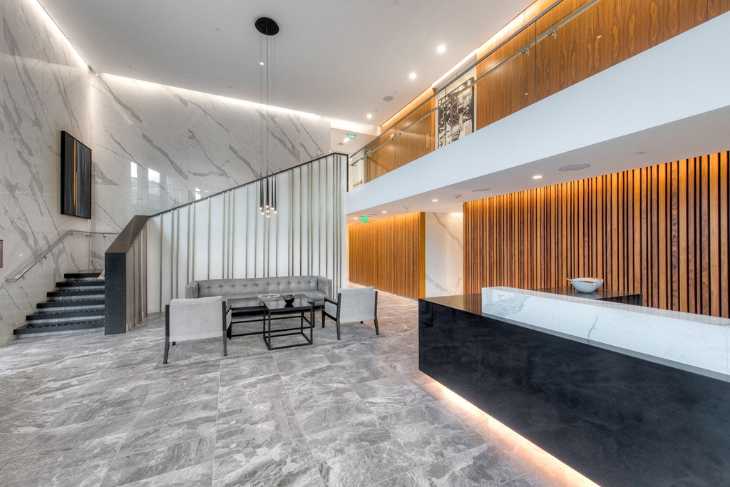 a lobby with a marble reception desk and a staircase