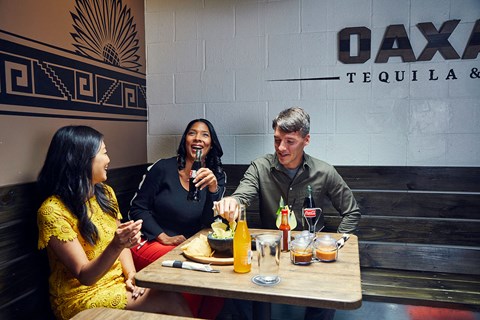 three people sitting at a table eating at a restaurant