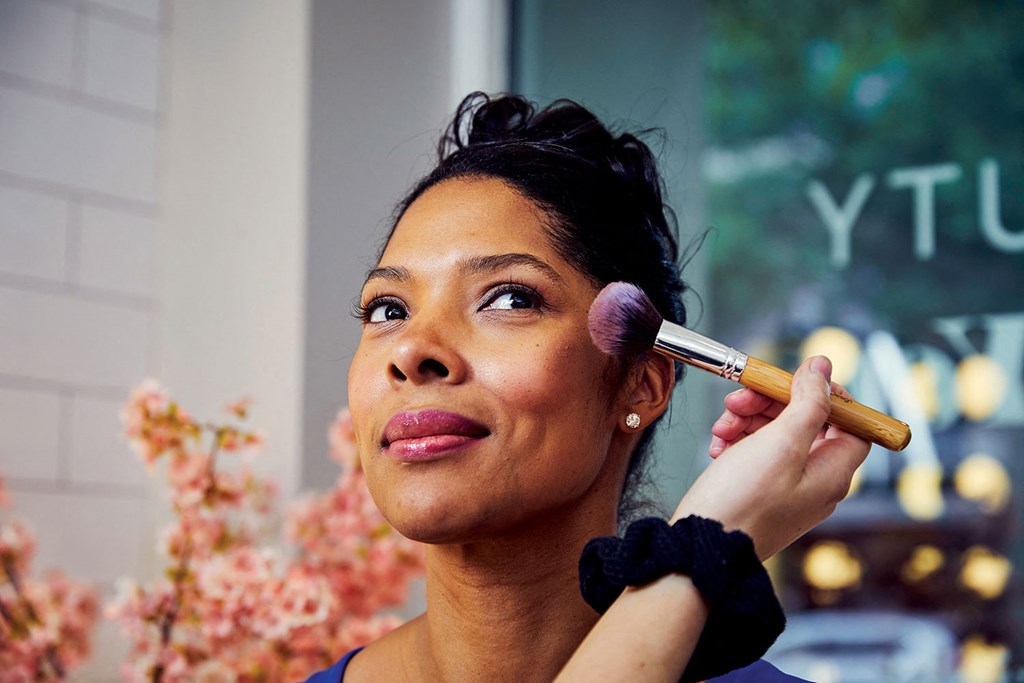 a woman applying makeup with a makeup brush