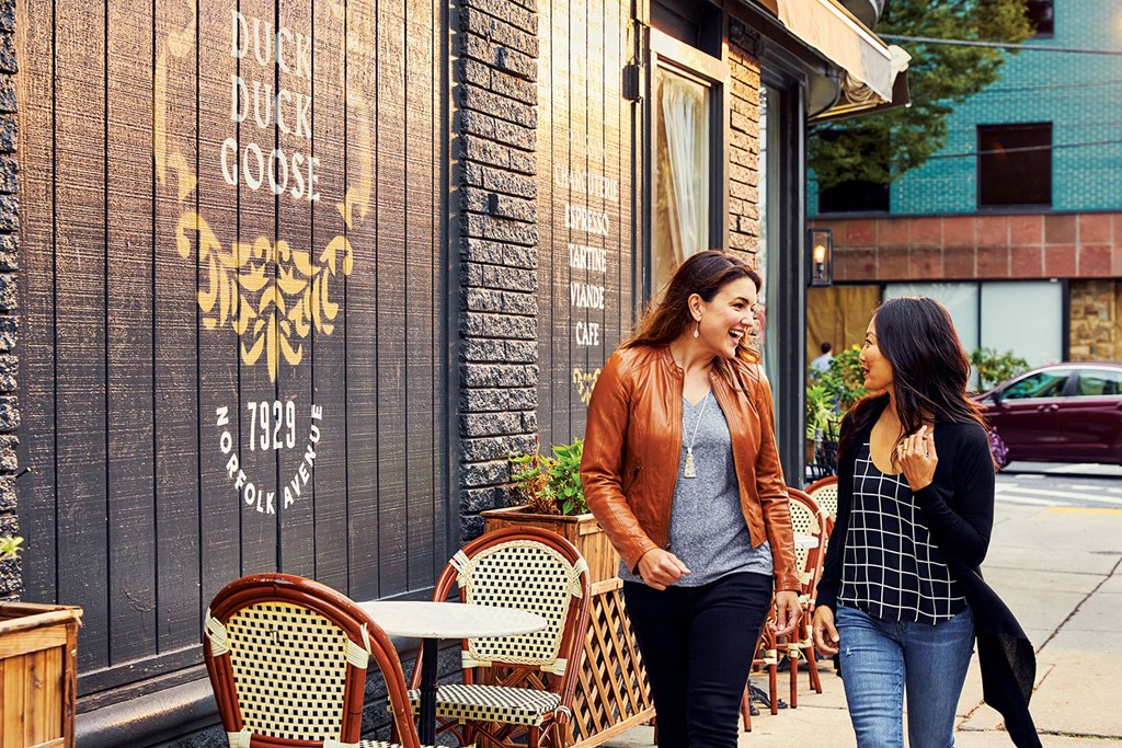 two women walking down a sidewalk outside of a restaurant