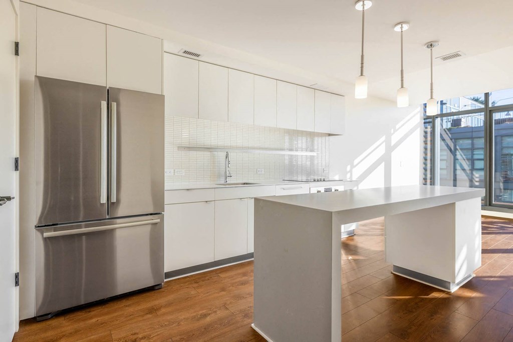 a white kitchen with a large island and stainless steel appliances