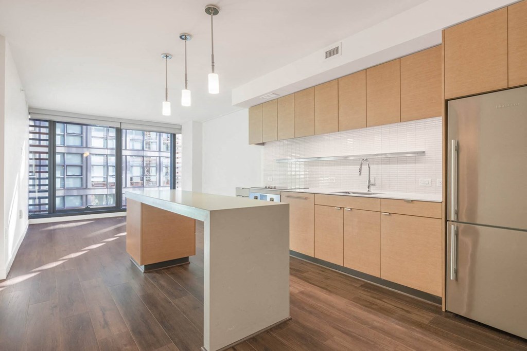a kitchen with a white island and a stainless steel refrigerator