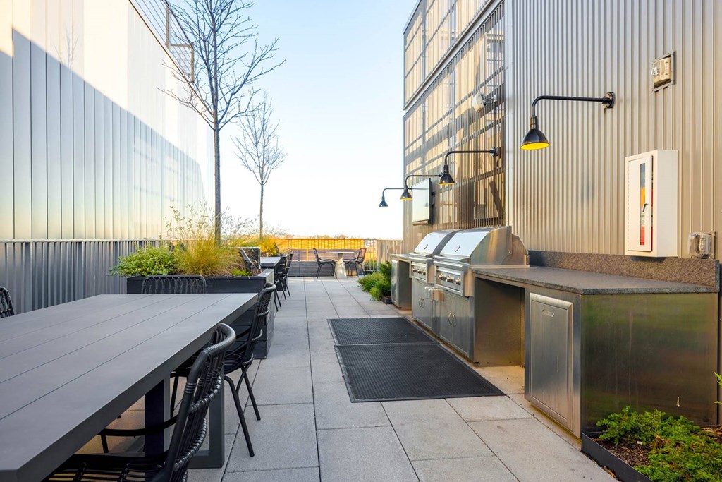 the outdoor patio of the building has a grill and tables