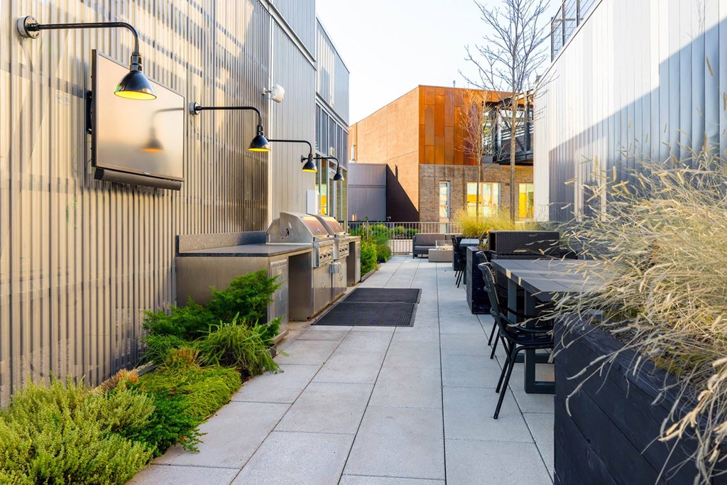a patio with tables and chairs and a grill next to a building