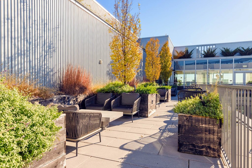 a patio with chairs and benches and a building in the background