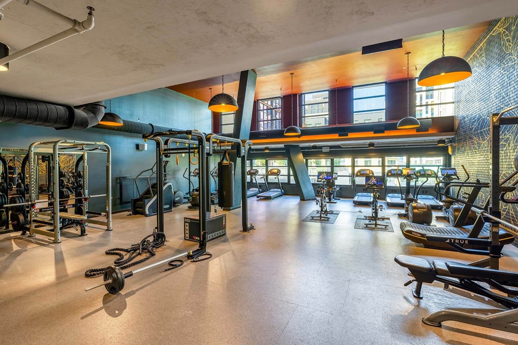 a workout room with weights and other exercise equipment in a building with windows