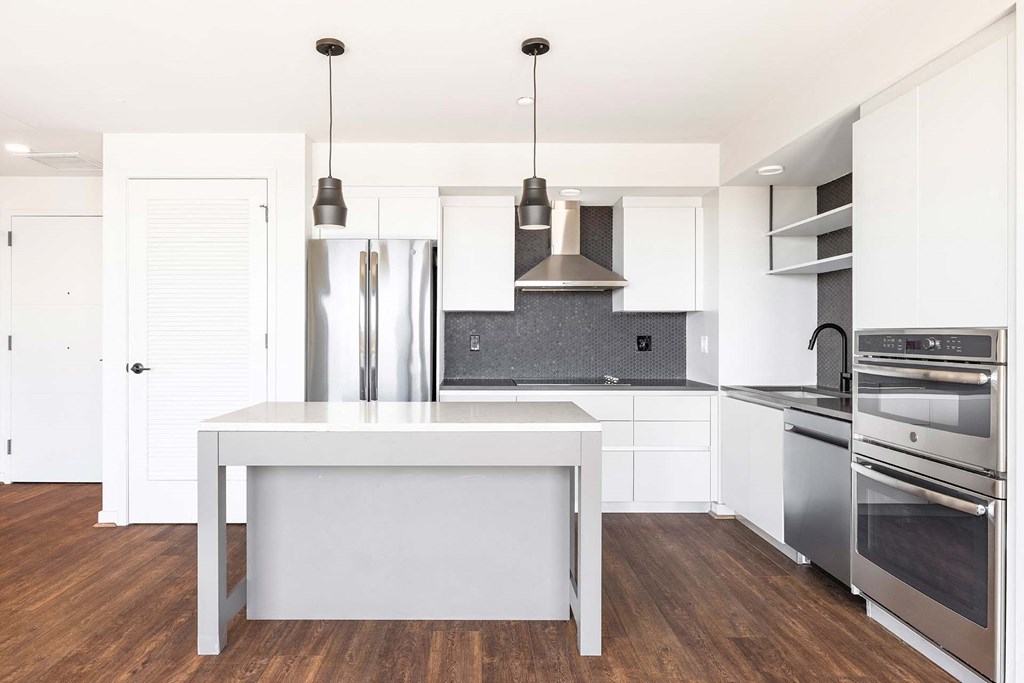 a white kitchen with stainless steel appliances and a white island