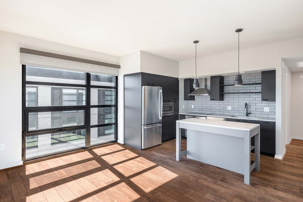 a kitchen with a large island and a stainless steel refrigerator