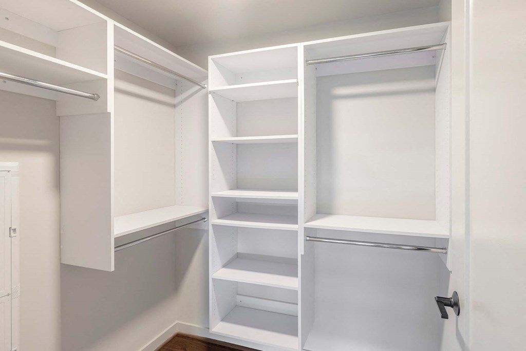 a walk in closet with white shelves and