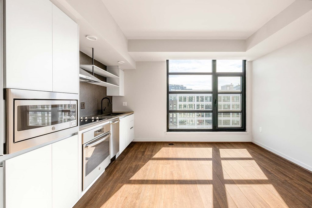 a kitchen with white cabinets and a large window