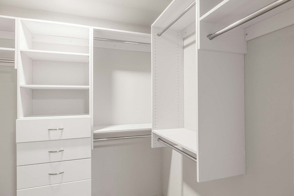 a white closet with white shelves and drawers and