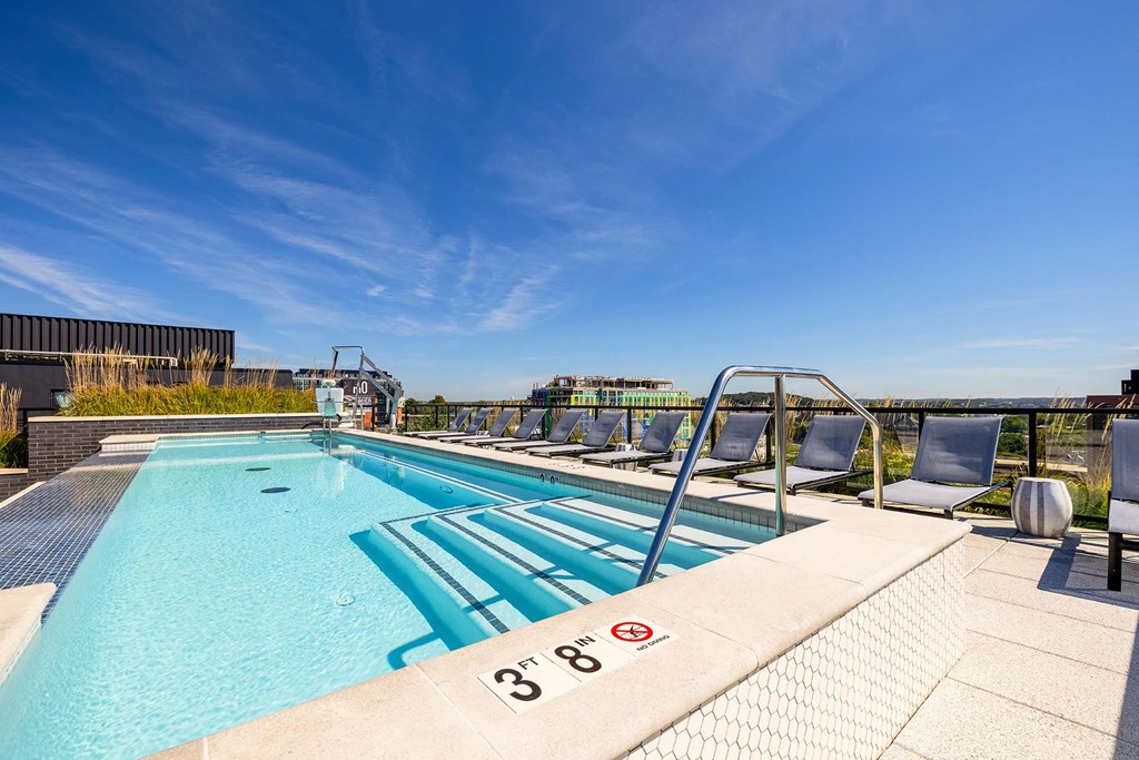 a swimming pool on the rooftop of a building with lounge chairs