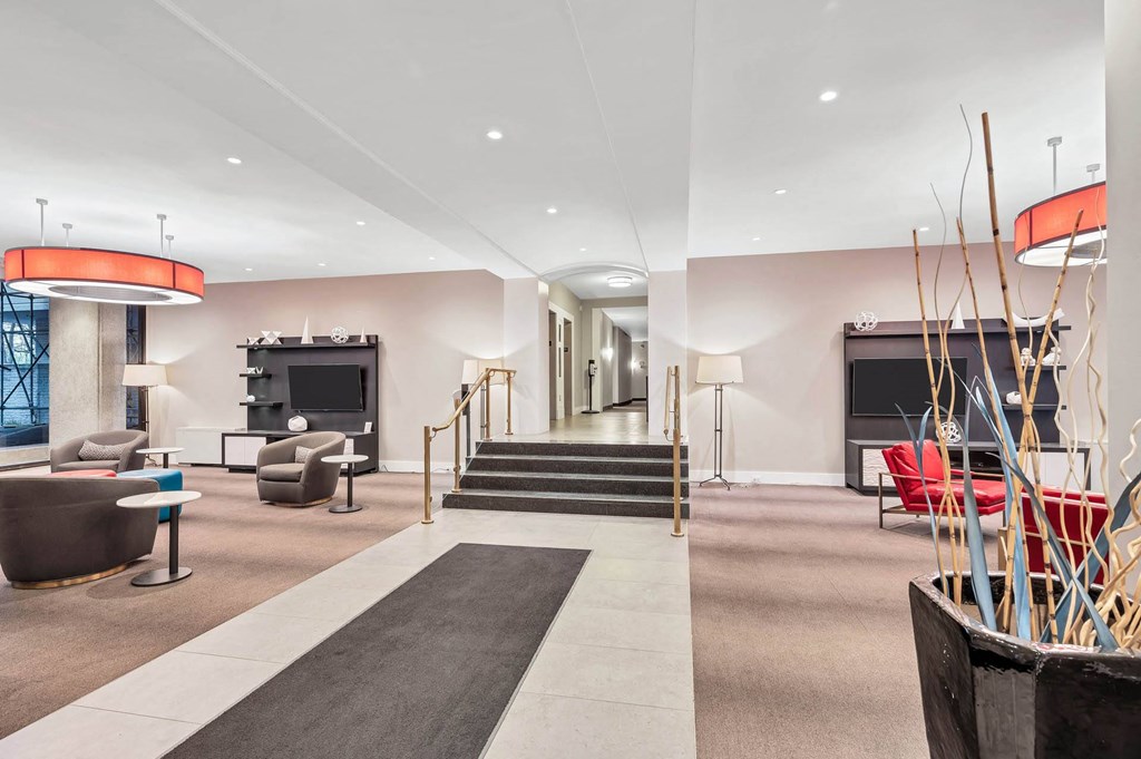 A modern living room with a grey carpet and a red couch.