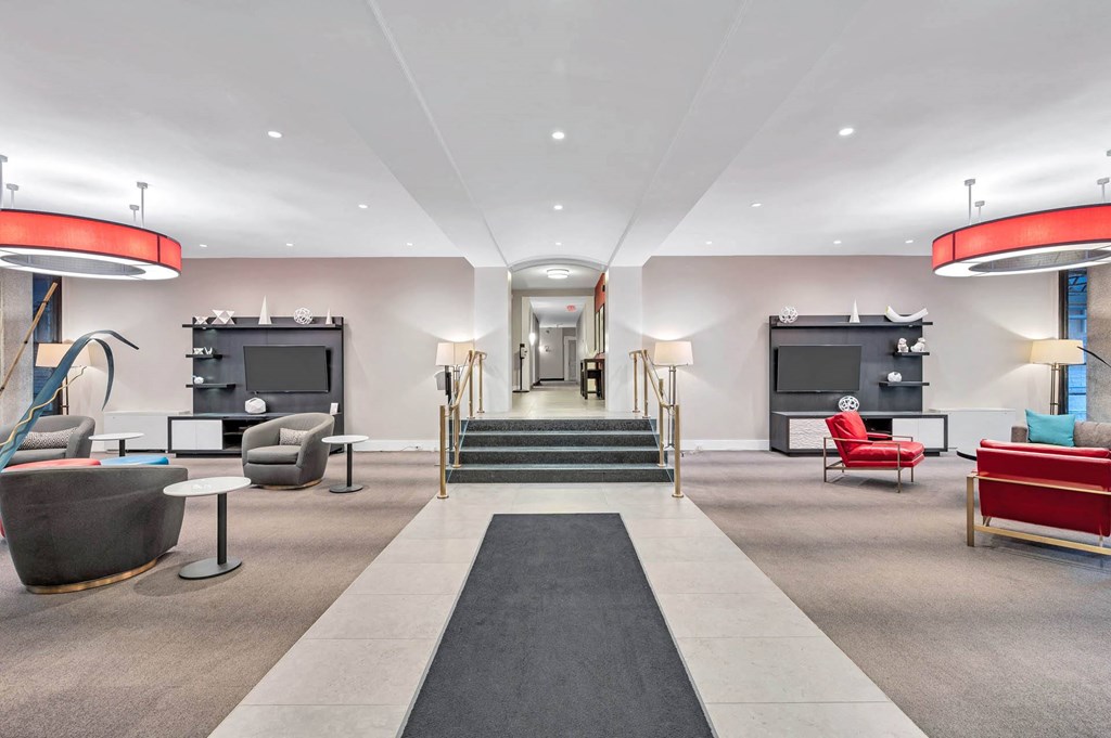A modern living room with a red and black sofa, a grey armchair, and a black and white rug.