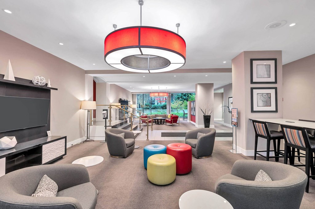 A modern living room with grey and red accent chairs and a red circular light fixture.
