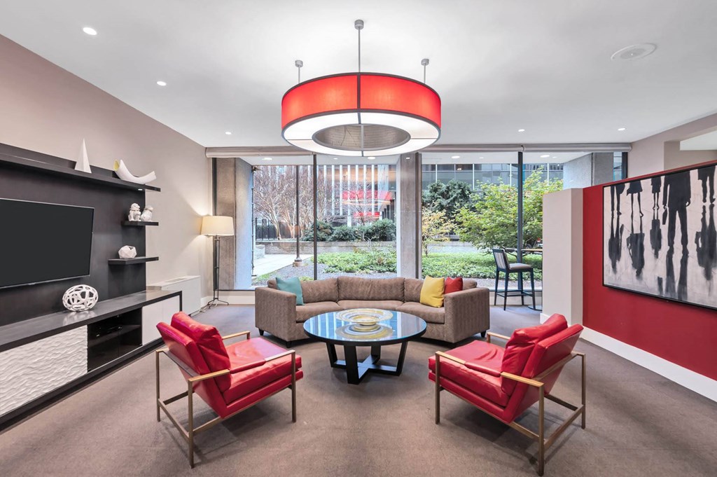 A living room with a red chair and a glass table.