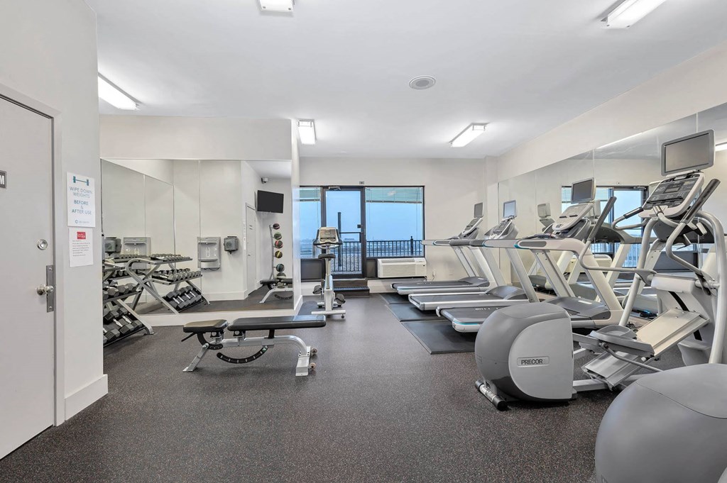 A gym with a variety of equipment including treadmills, weights, and exercise machines.