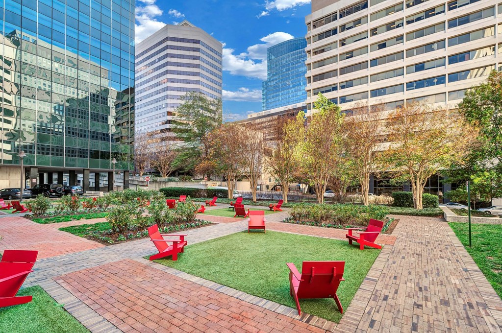 A park with red chairs and a brick pathway.