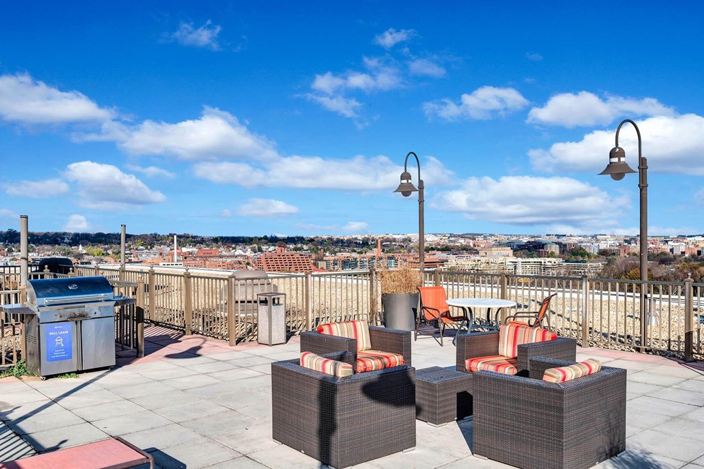 a rooftop patio with furniture and a city in the background