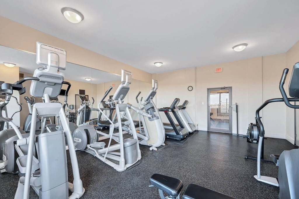 A gym with a variety of exercise equipment including treadmills, elliptical machines, and weight machines.