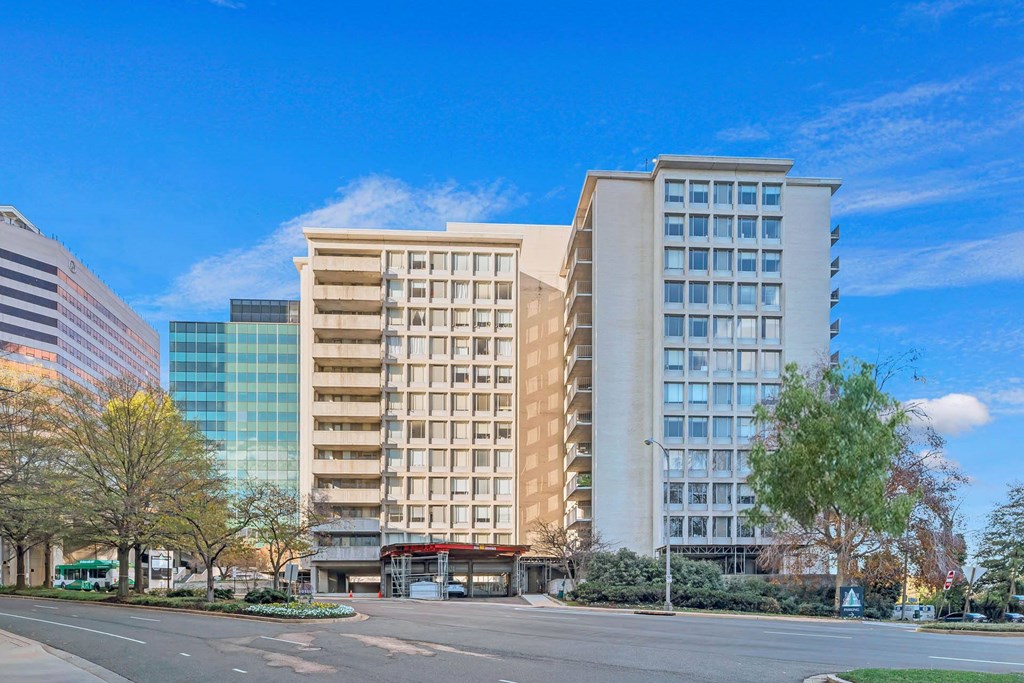 A large building with a beige facade stands in front of a blue sky.