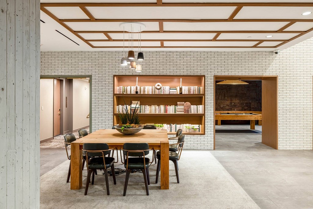 a dining room with a wooden table and chairs and a book shelf