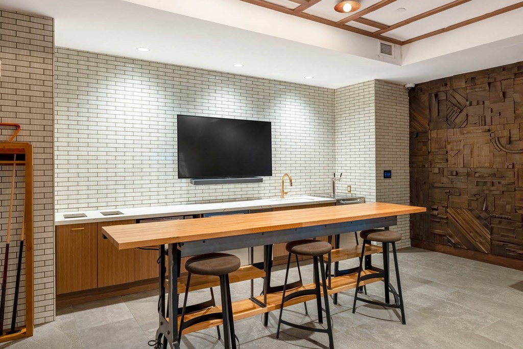 a bar with four stools in a room with a television