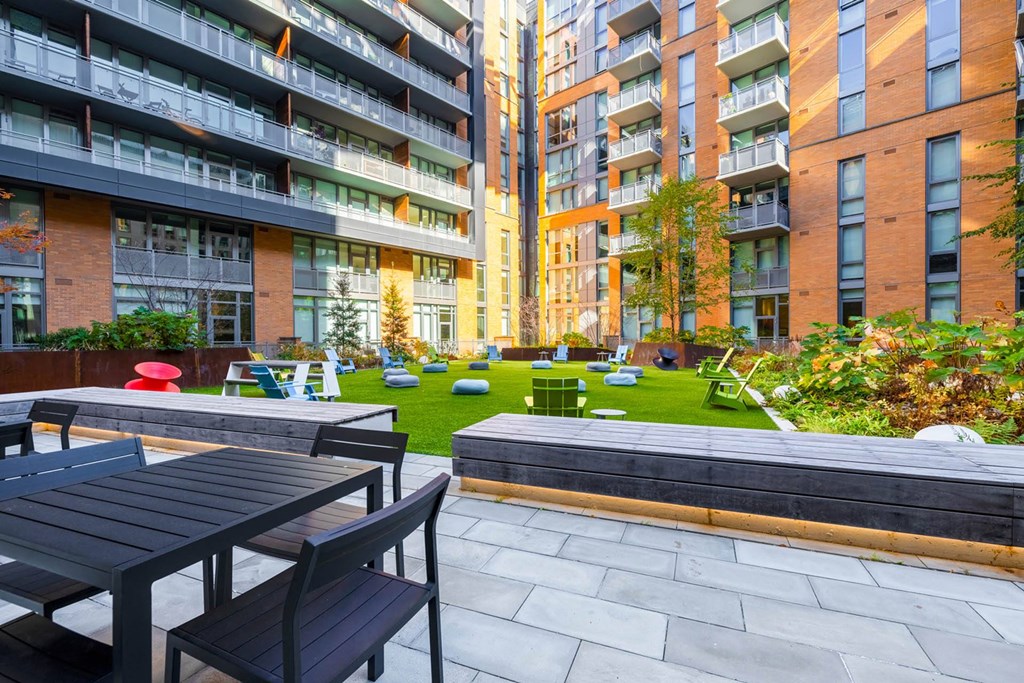 an outdoor area with tables and chairs in front of an apartment building