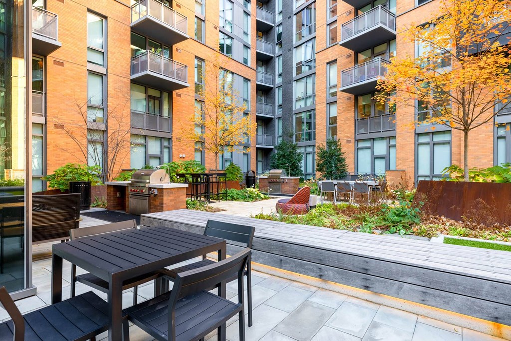 an outdoor patio with tables and chairs in front of an apartment building