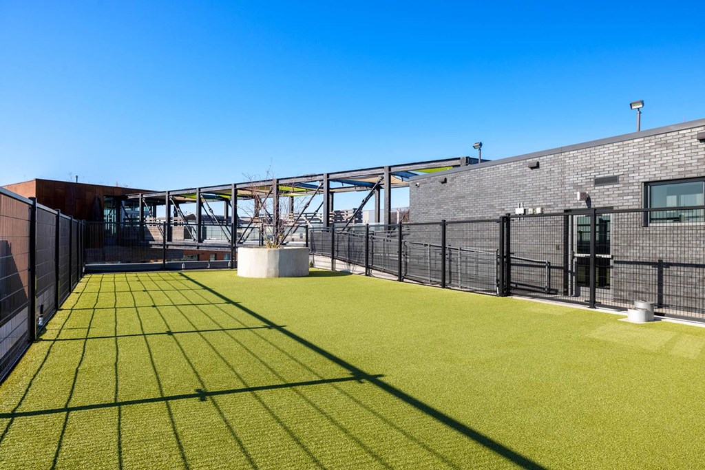 the yard of a brick building with a green lawn and a fence