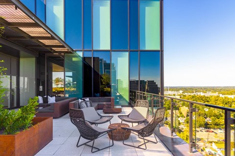 a balcony with a view of a city and a patio with chairs