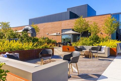 a patio with chairs and tables in front of a building