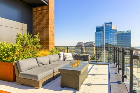 a rooftop terrace with a couch and a table with a view of the city