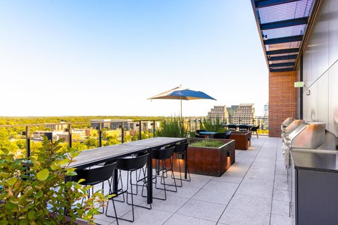 a rooftop terrace with a table and chairs and an umbrella